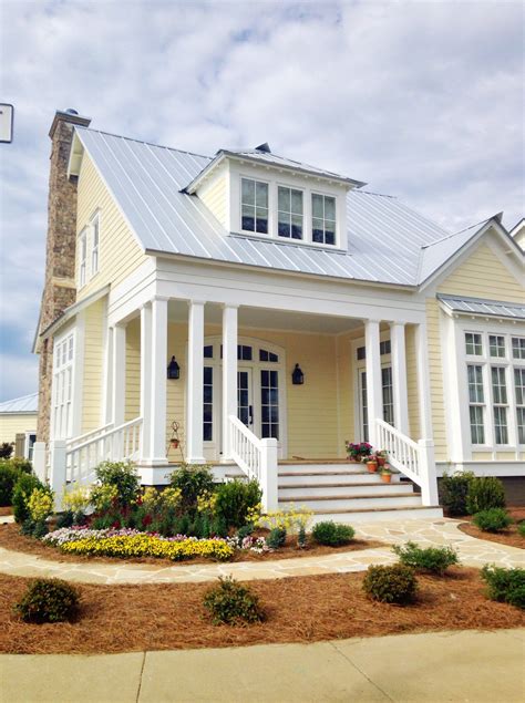 2 story pale yellow house with porch with metal roofing|yellow wall house ideas.